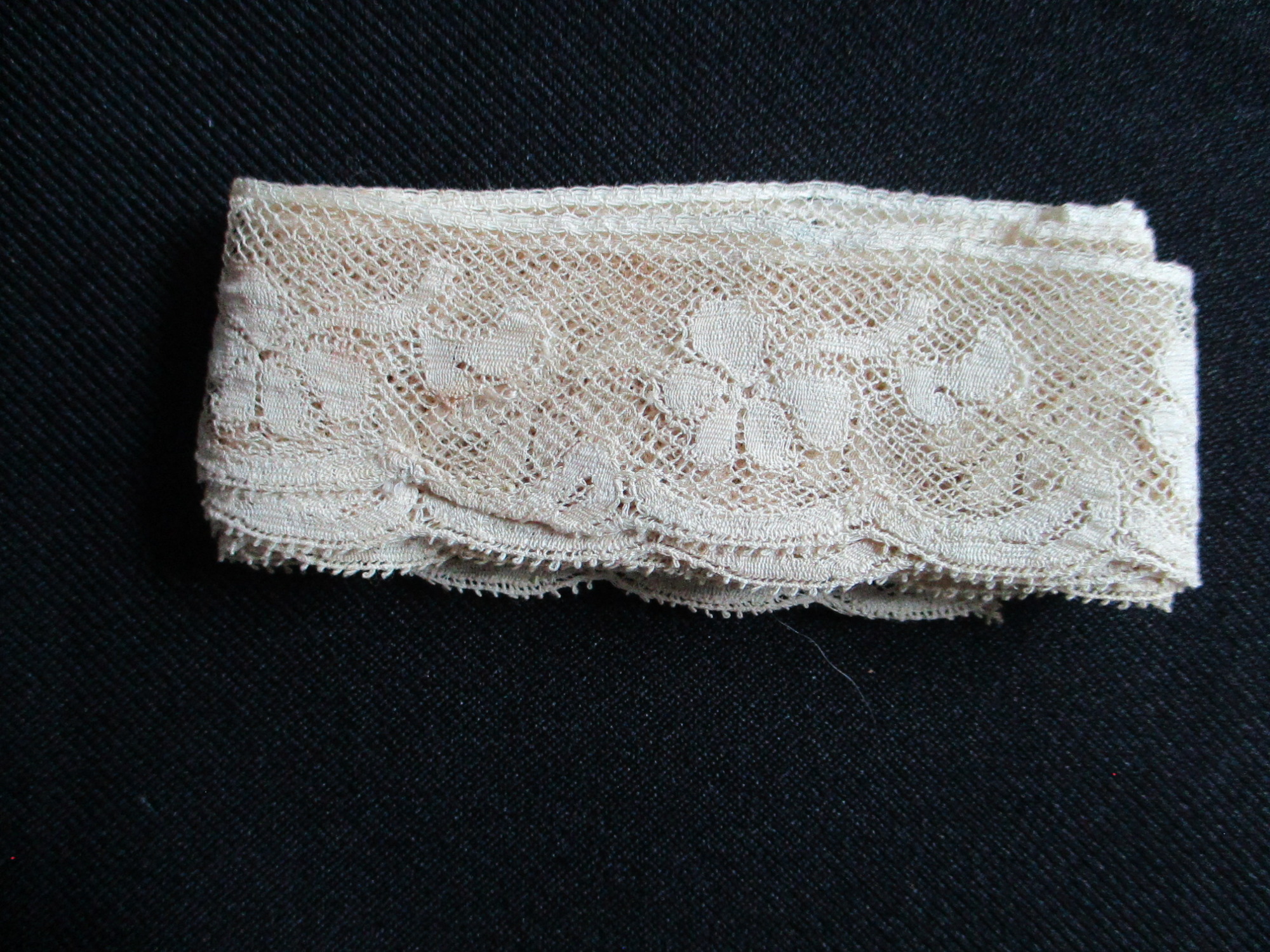 Length of folded silk lace trim.: Length of folded cream silk lace trim. (ii)