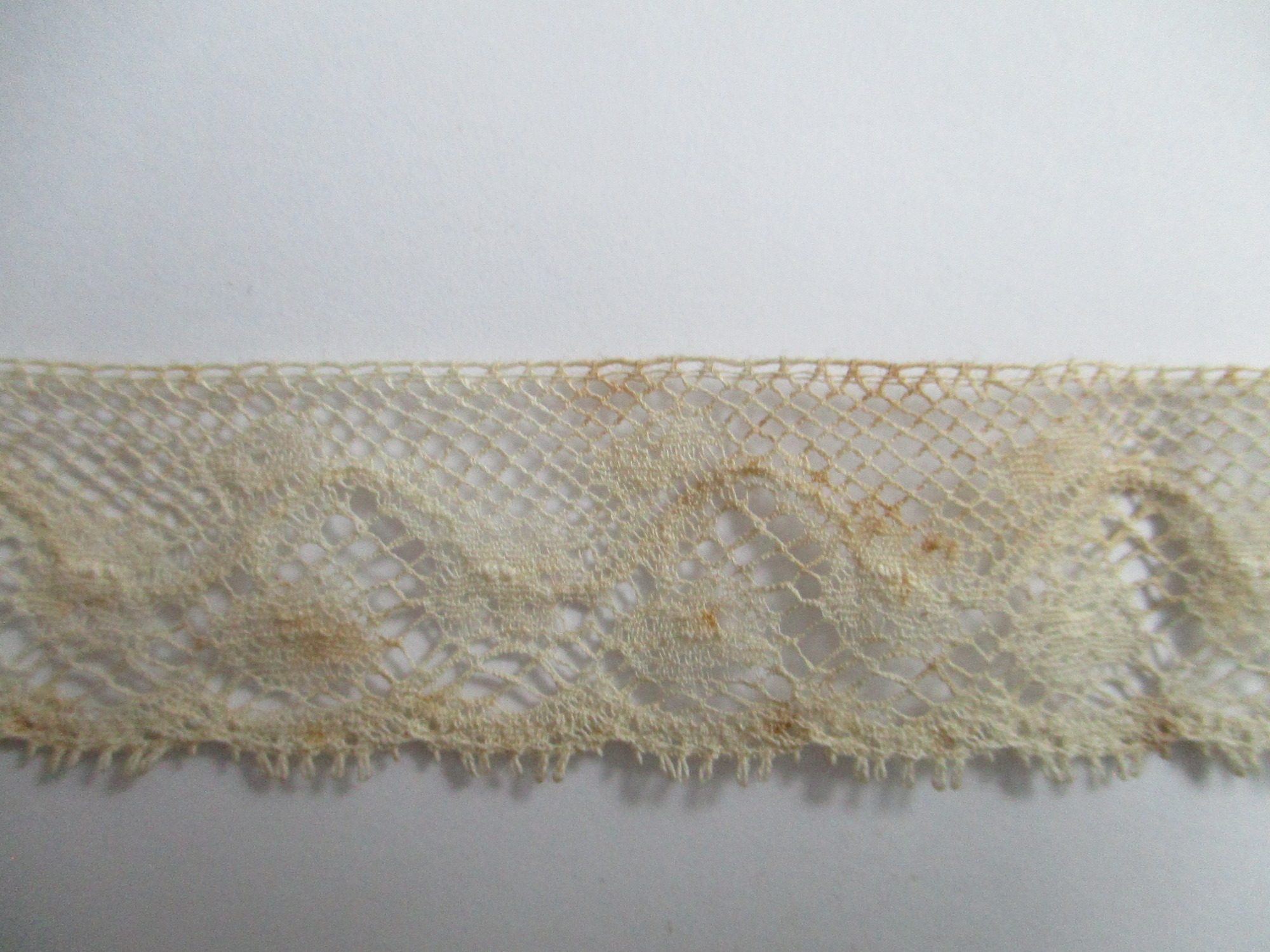 Length of lace trim.: Close-up image of cream lace trim/edging.