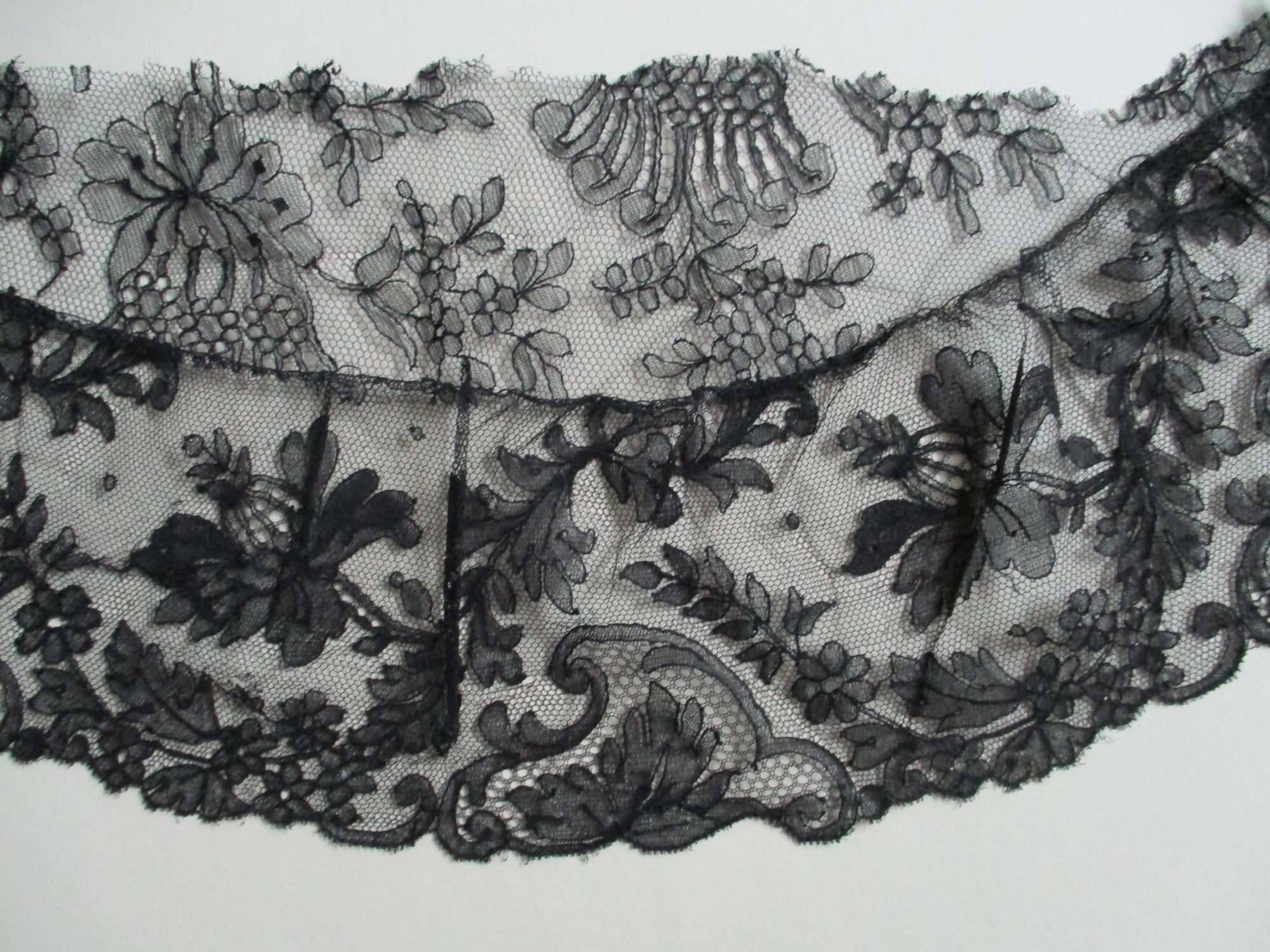 Piece of black lace netting: Black lace netting lower edge detail.