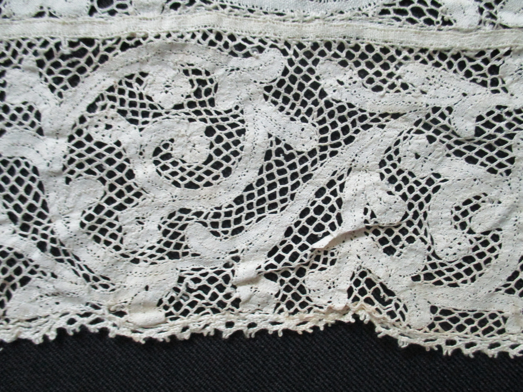 Piece of cream cotton lace.: Detail of swirl design on cream lace.