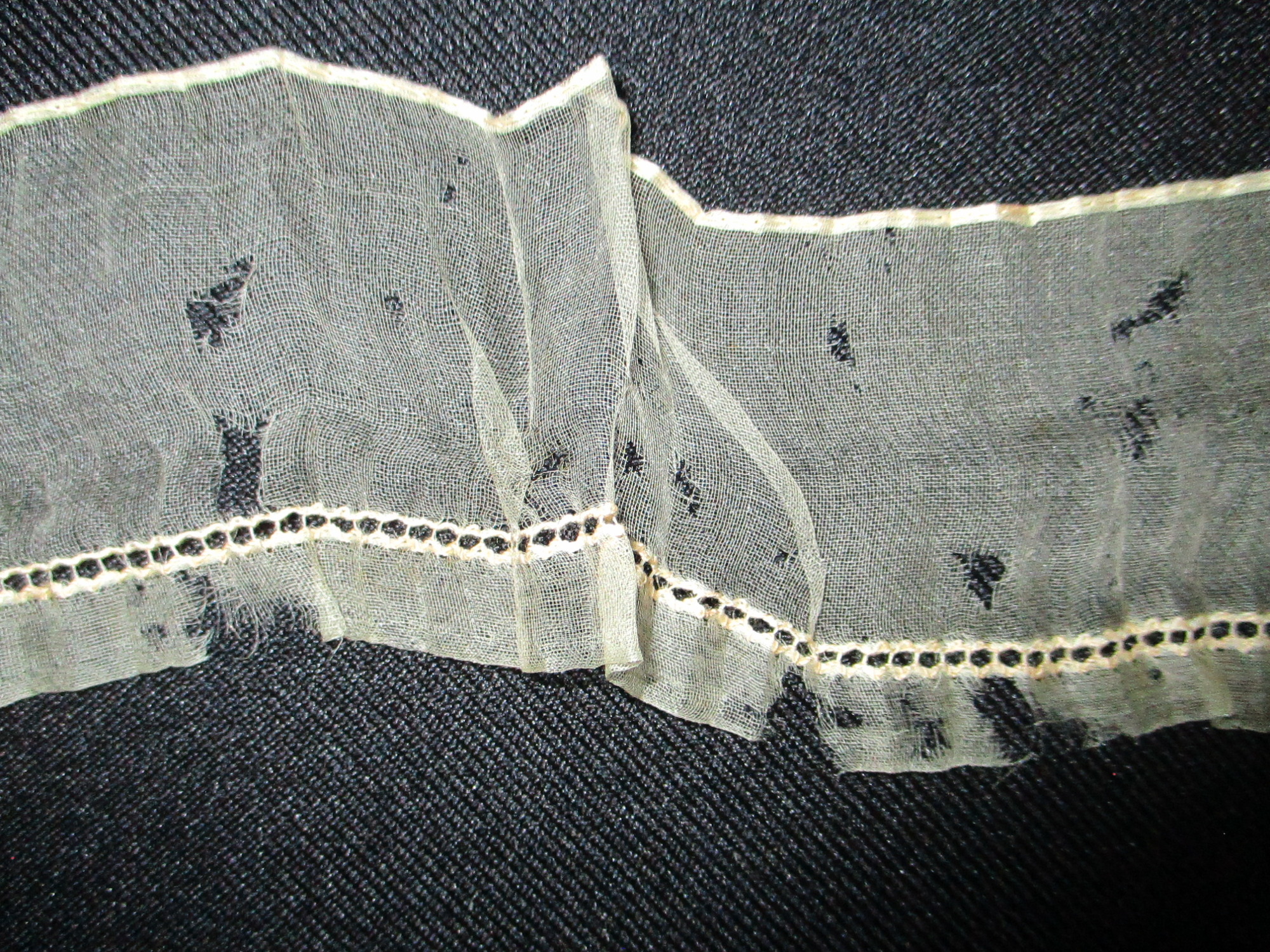 Piece of cream silk edging/trim.: Close-up of cream silk ribbon/edging. (ii)