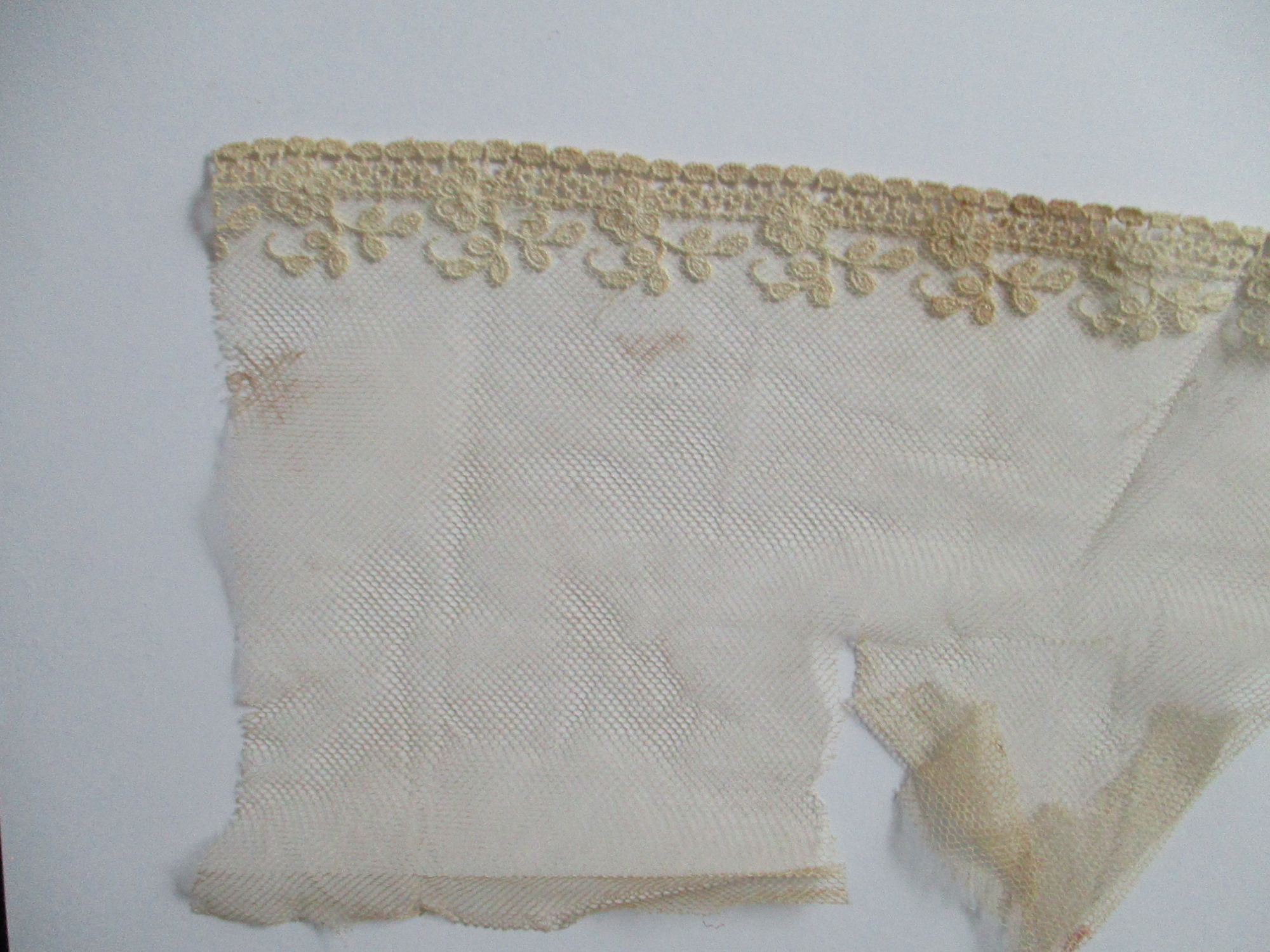 Piece of decorated nylon netting.: End detail of decorated cream netting. (i)