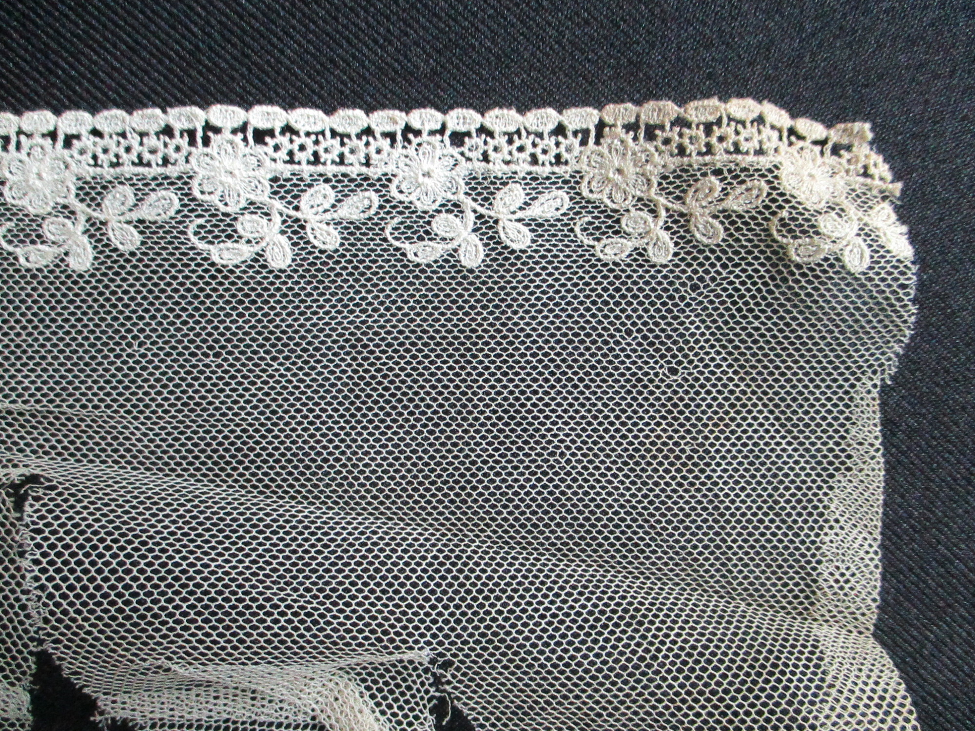 Piece of decorated nylon netting.: End detail of decorated cream netting. (ii)