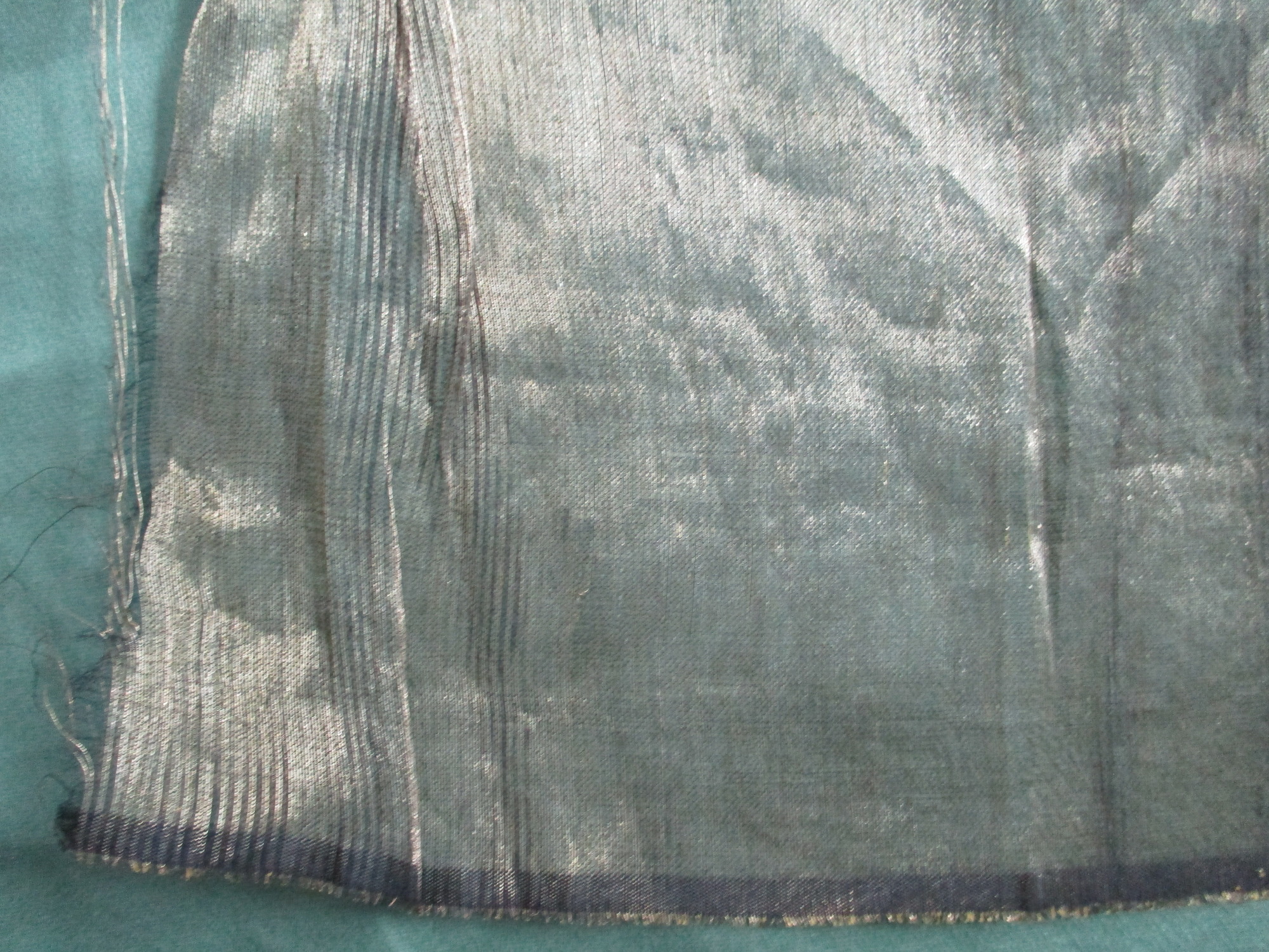 Piece of gold satin material: Frayed corner of gold satin material.