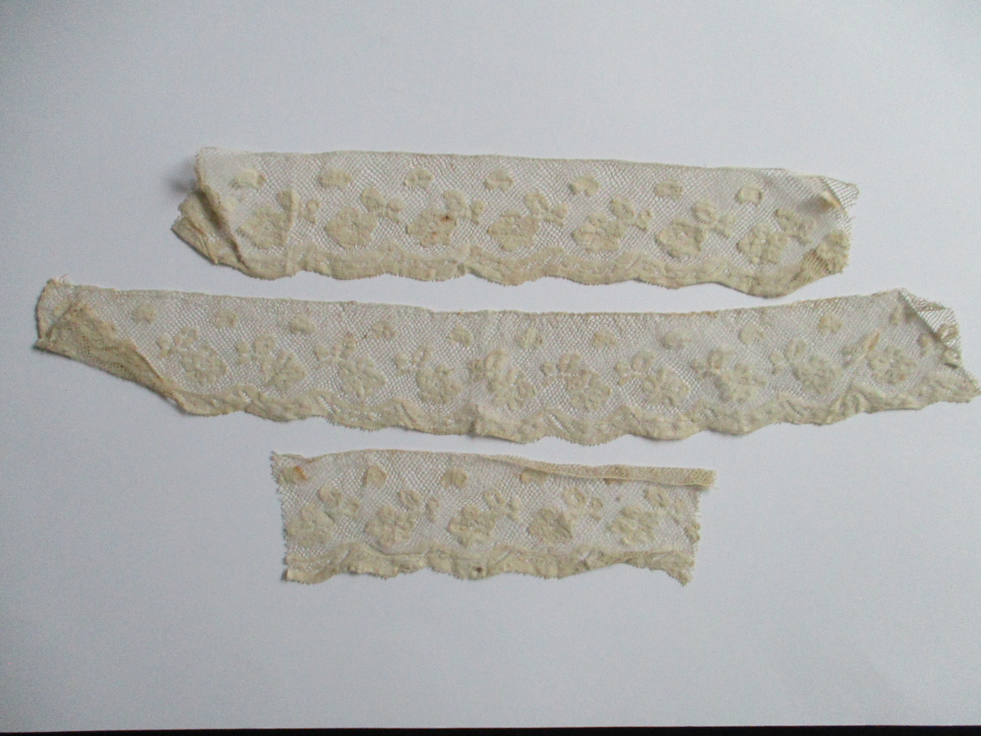 Three pieces of cream silk lace trim.