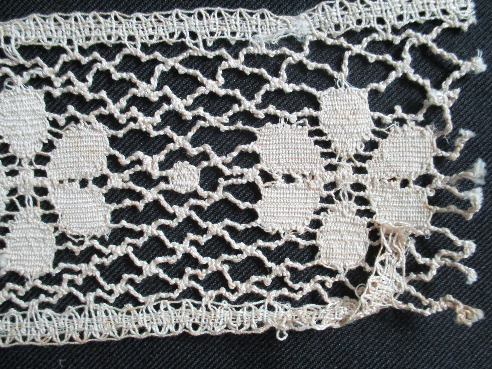 Two pieces of cream cotton lace: Close up of cotton lace border.