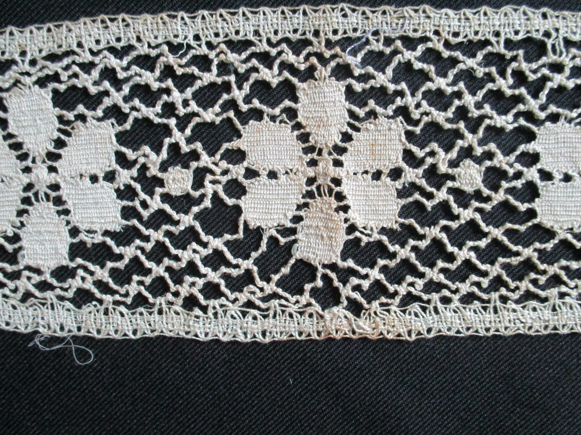 Two pieces of cream cotton lace: Flower detail of cotton lace border.