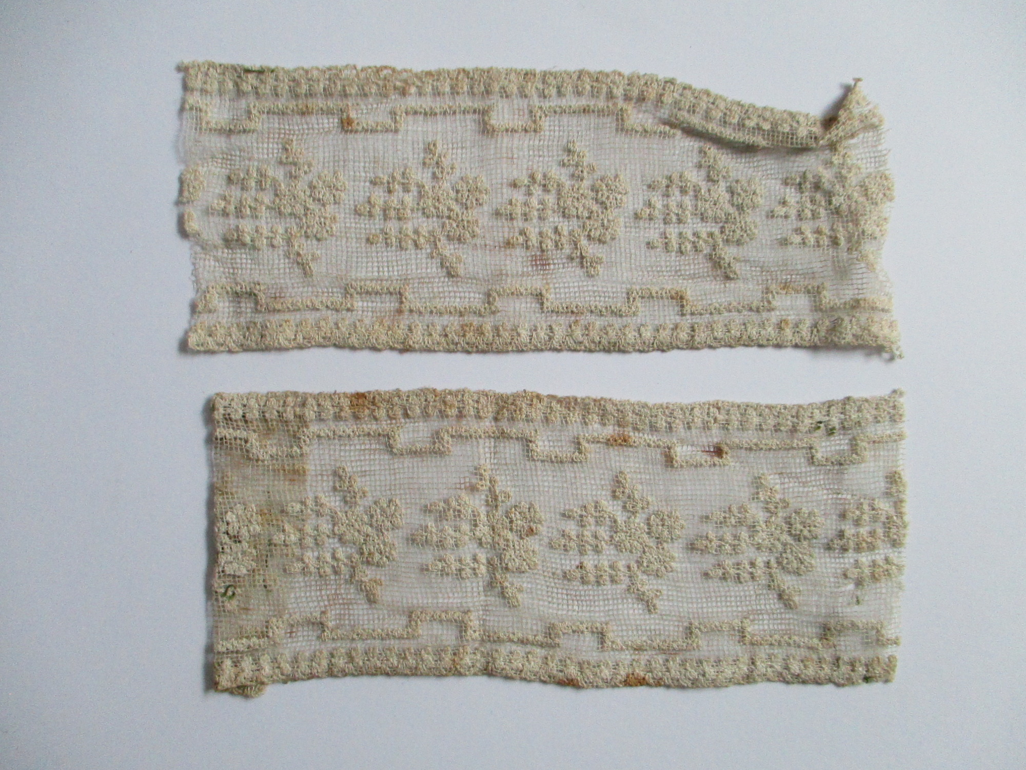 Two pieces of decorated cream netting.